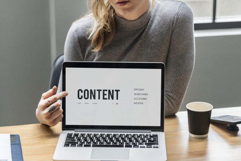Blond woman pointing at a laptop screen